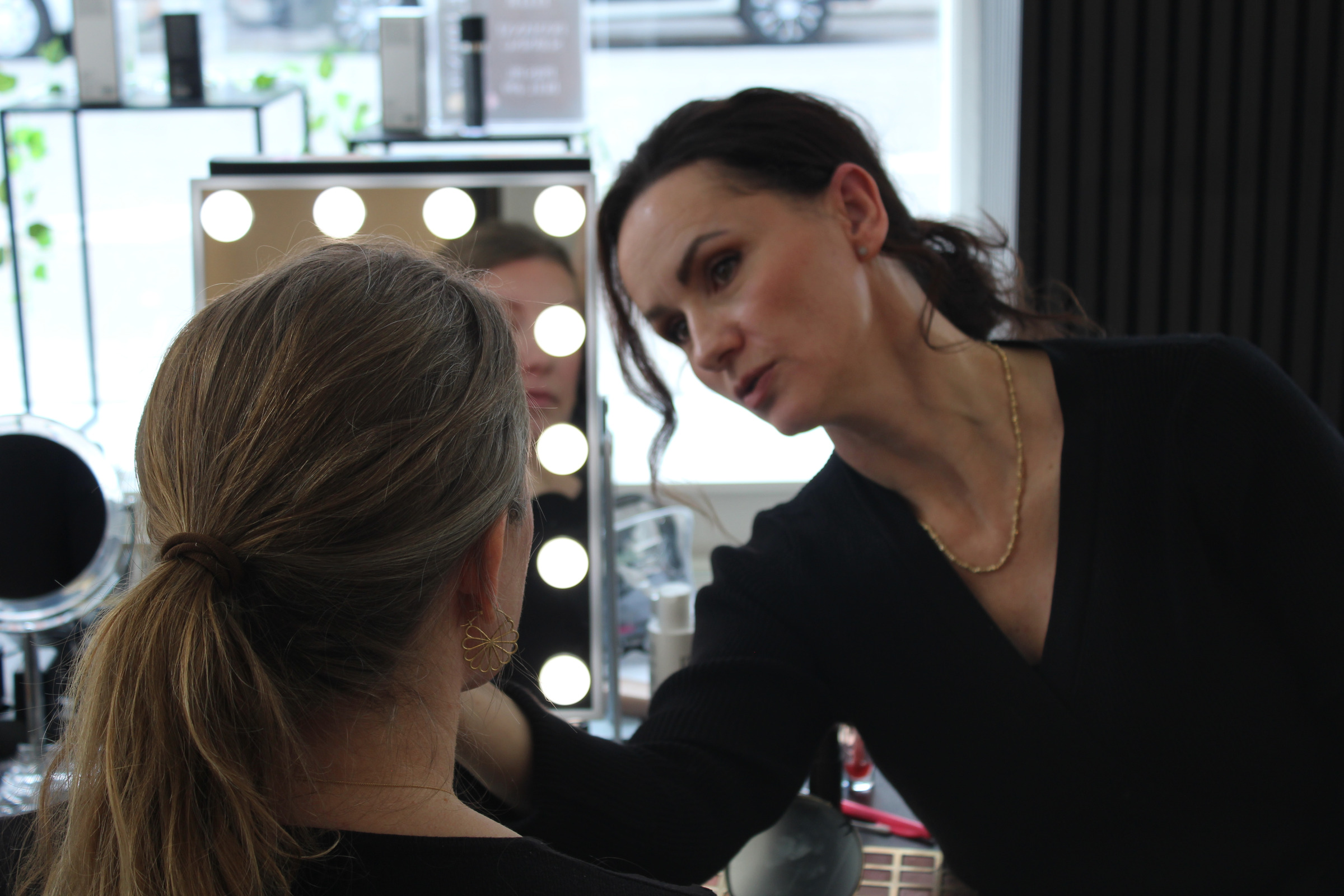 Kosmetolog hos IZANEL guider kunden ved makeupspejlet på Frederiksberg